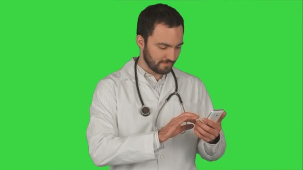 Medical male doctor sending a message with his cellphone while smiling and standing on a Green Screen, Chroma Key — Stock Video