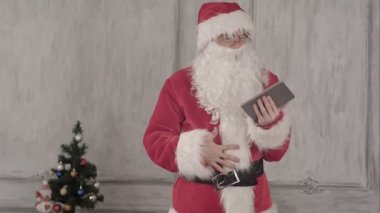 Noel Baba beyaz arka plan üzerinde tablet bilgisayar kullanarak