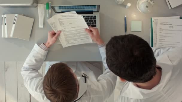 Dokter ondertekening van een medisch rapport in zijn kantoor. Bovenaanzicht — Stockvideo