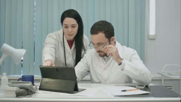 Erkek ve kadın doktorlar tablet kullanarak sonuçlarını konuşmak — Stok video