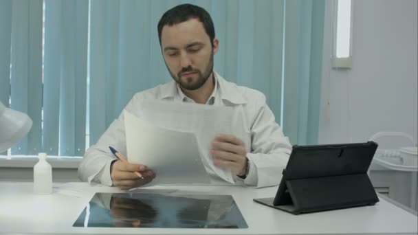 Koncentratu mężczyzna lekarz patrząc na zdjęcia RTG w gabinecie lekarskim — Wideo stockowe