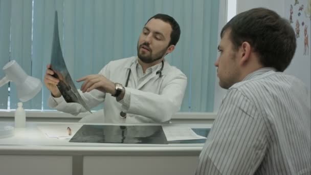 Homme barbu médecin à la clinique montrent des rayons X au client masculin . — Video