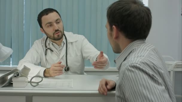 Αρσενικό γενειοφόρος γιατρός στο clinicmeasure τον παλμό της αρσενικό πελάτη. — Αρχείο Βίντεο