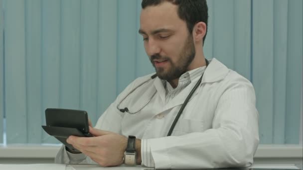 Médico barbudo sinistro com uma calculadora. cálculo do preço — Vídeo de Stock