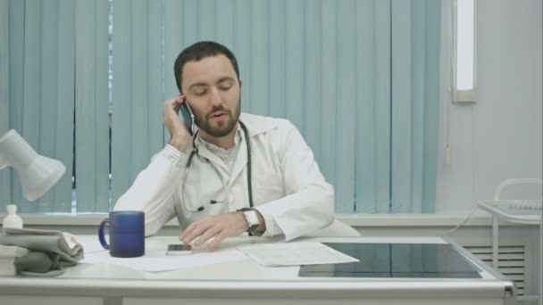 Médico masculino hablando por celular en un hospital moderno en el interior — Vídeo de stock