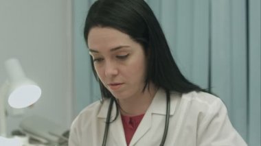 Kadın doktor tıbbi ofis içinde sonuçları bir elektrokardiyogram ve alır notlar analiz eder.