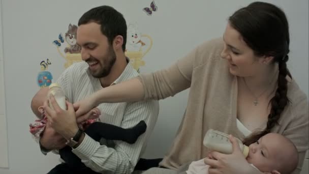 Happy young parents feed newborn twins from a bottle — Stock Video