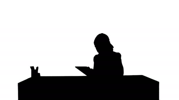 Γυναίκα των επιχειρήσεων σιλουέτα κάθεται στο γραφείο της, χρησιμοποιώντας έναν υπολογιστή δισκίο — Αρχείο Βίντεο