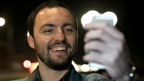 Divertido hombre está tomando una selfie con un teléfono inteligente — Vídeo de stock