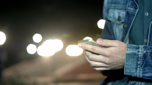 Un uomo invia un messaggio via smartphone durante la notte in città — Video Stock