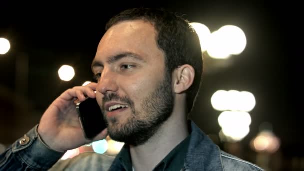 Mladý muž hovoří s mobilním telefonem chůze v nočním městě — Stock video