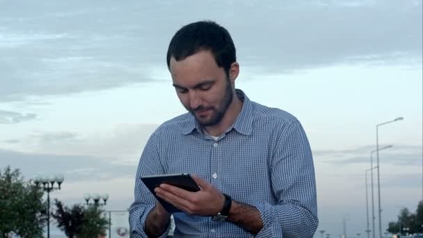 Homem usando seu computador tablet lá fora ao pôr do sol — Vídeo de Stock