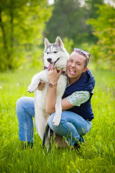 Mädchen im Gras umarmt Husky — Stockfoto