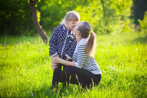 Glückliche junge Frau küsste ein süßes kleines Mädchen — Stockfoto