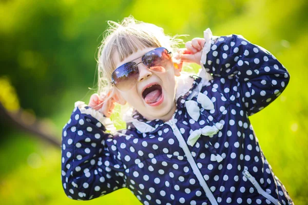 Lilla flickan liggande på gräs solglasögon — Stockfoto