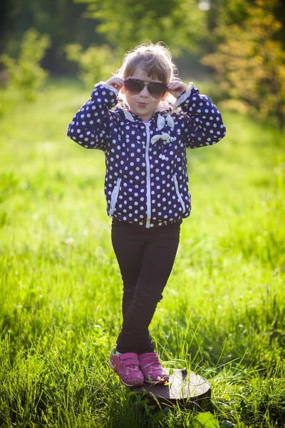 Lilla flickan liggande på gräs solglasögon — Stockfoto