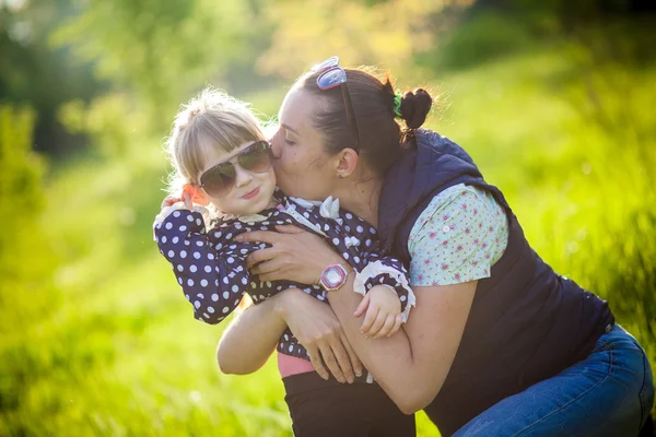 亲吻她的母亲在公园里的小女孩 — 图库照片