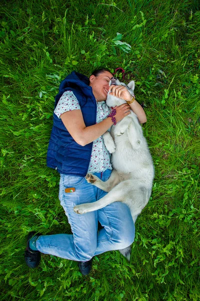 Chica acostada con su cachorro en la hierba verde —  Fotos de Stock