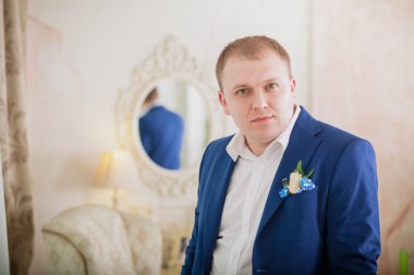 Muhteşem gülümseyen damat. Suite kapalı pencere pervazına üzerinde oturan bir ilik ile yakışıklı adam