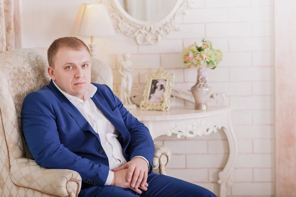 Muhteşem gülümseyen damat. Suite kapalı pencere pervazına üzerinde oturan bir ilik ile yakışıklı adam