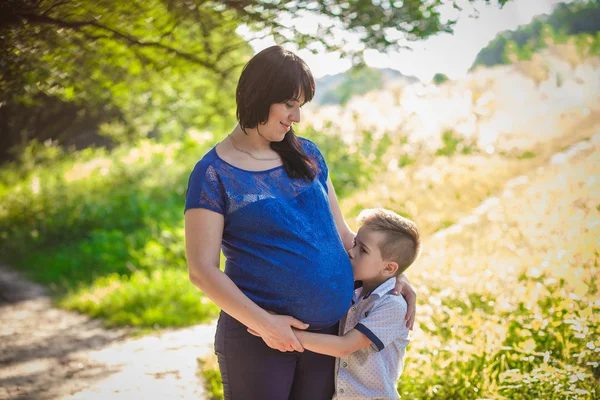 Kleiner Junge umarmt schwangere Mutter — Stockfoto