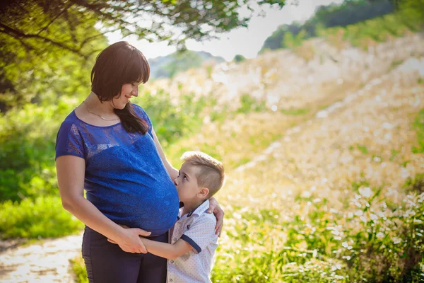 Pequeño niño abrazando embarazada madre —  Fotos de Stock