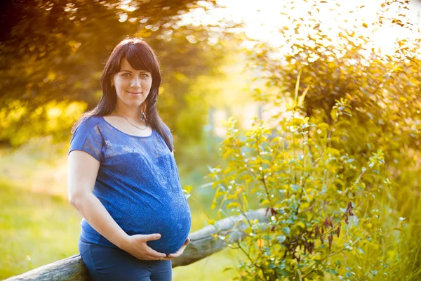 Mujer embarazada posando en un jardín verde —  Fotos de Stock