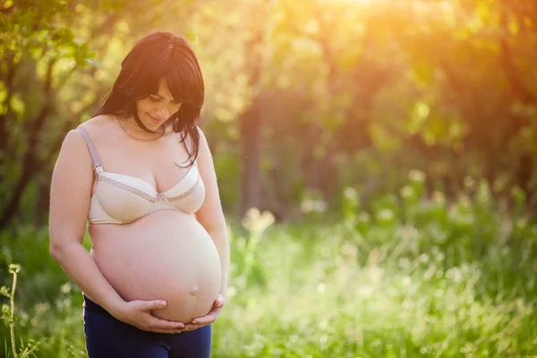 Le ventre de la femme enceinte sur le parc — Photo