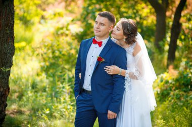 Şık gelin ve damat düğün günü dışarıda birlikte poz veriyorlar.