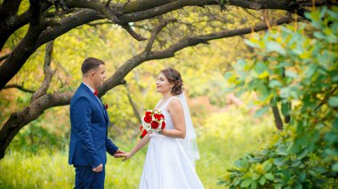 Şık gelin ve damat düğün günü dışarıda birlikte poz veriyorlar.