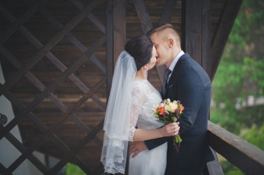 Düğün çift, el ele tutuşarak ve gülümseyen bir parkta duran güzel genç gelin damat