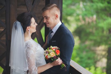 Düğün çift, el ele tutuşarak ve gülümseyen bir parkta duran güzel genç gelin damat