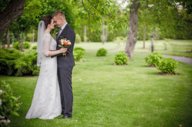 Düğün çift, el ele tutuşarak ve gülümseyen bir parkta duran güzel genç gelin damat