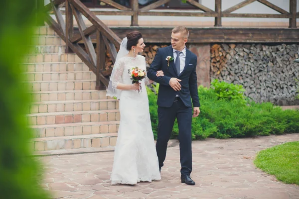 Esküvő házaspár, gyönyörű fiatal menyasszony vőlegény kezét és mosolyogva parkban álló — Stock Fotó