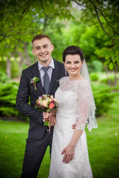 Wedding couple, beautiful young bride groom standing in a park holding hands and smiling — Stock Photo, Image