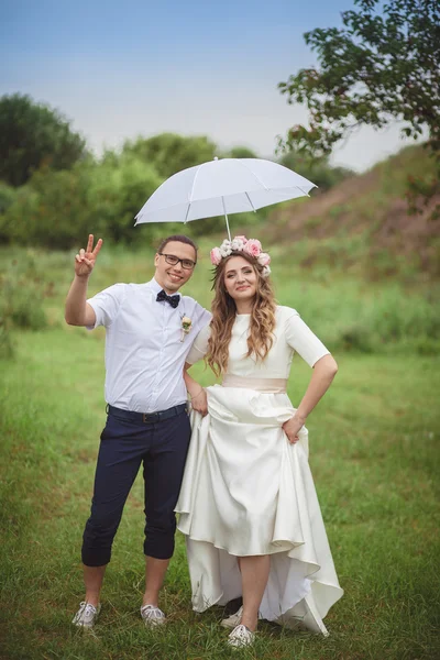 Panna młoda i pan młody uśmiech przytulanie pod biały parasol — Zdjęcie stockowe