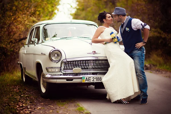 Жених и невеста возле машины — стоковое фото