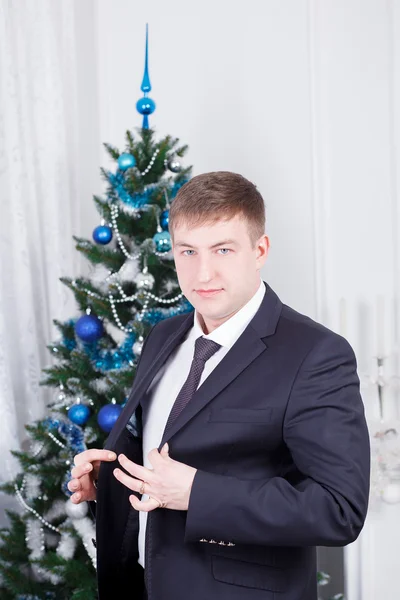 Man in pak op de achtergrond van de kerstboom — Stockfoto