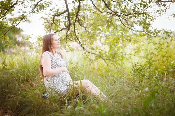 Enceinte assise sur l'herbe — Photo