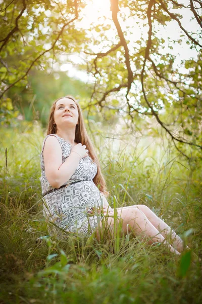 Беременная сидит на траве — стоковое фото