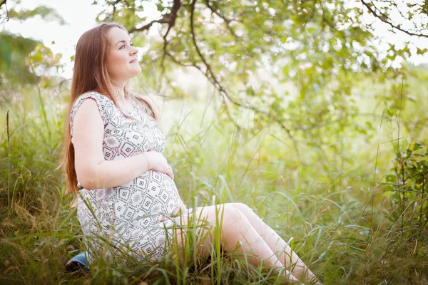 Schwangere sitzt im Gras — Stockfoto