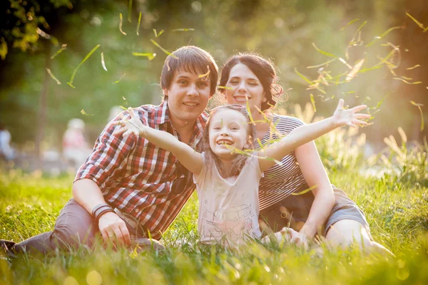 Dad mother and daughter sitting on the grass — Stock Photo, Image