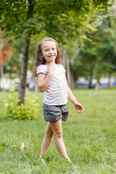 Malá holčička stojí na trávě — Stock fotografie