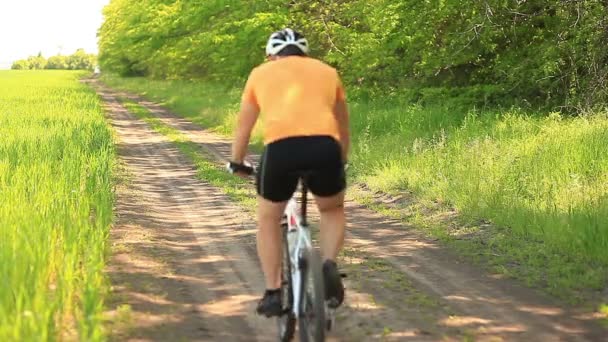 Un ciclista en un camino de tierra — Vídeos de Stock