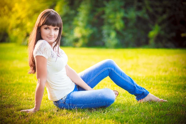 Jeans menina sentado na grama — Fotografia de Stock