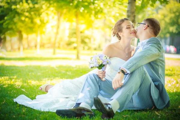 Gelin ve damat çimenlerin üzerine oturmuş — Stok fotoğraf