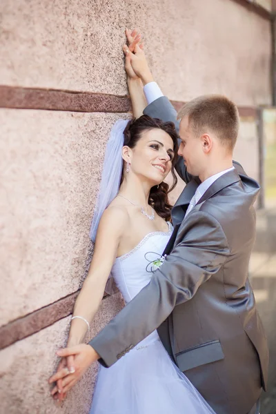 Noivo e noiva perto da parede — Fotografia de Stock