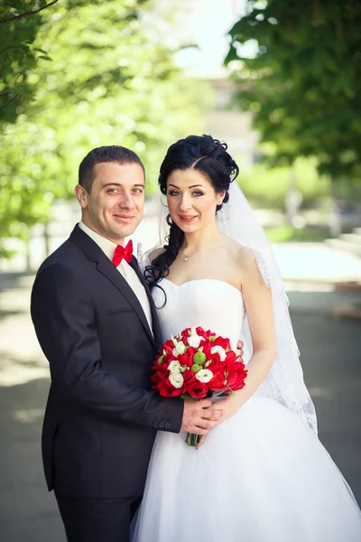 O noivo, a noiva, buquê vermelho — Fotografia de Stock