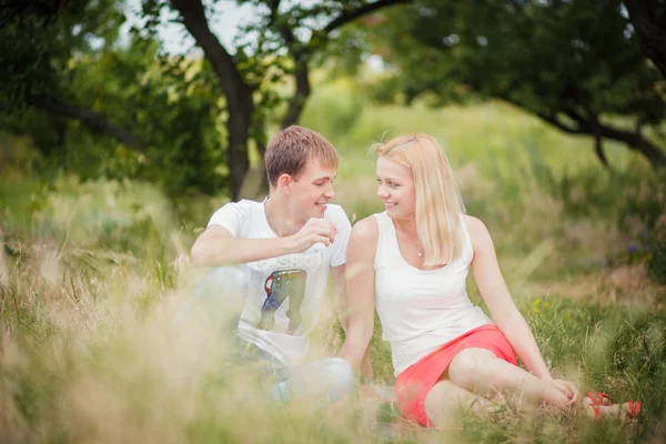 Pareja sentada en la hierba en el parque —  Fotos de Stock