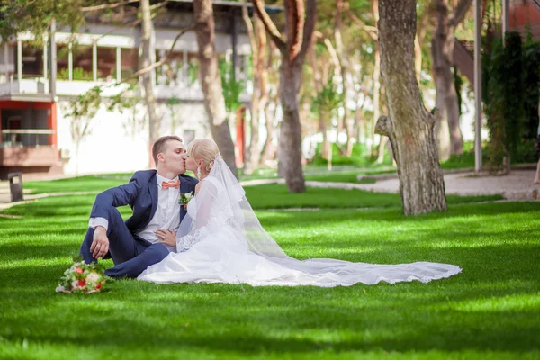 Νύφη και γαμπρός κάθεται στο πράσινο γρασίδι — Φωτογραφία Αρχείου